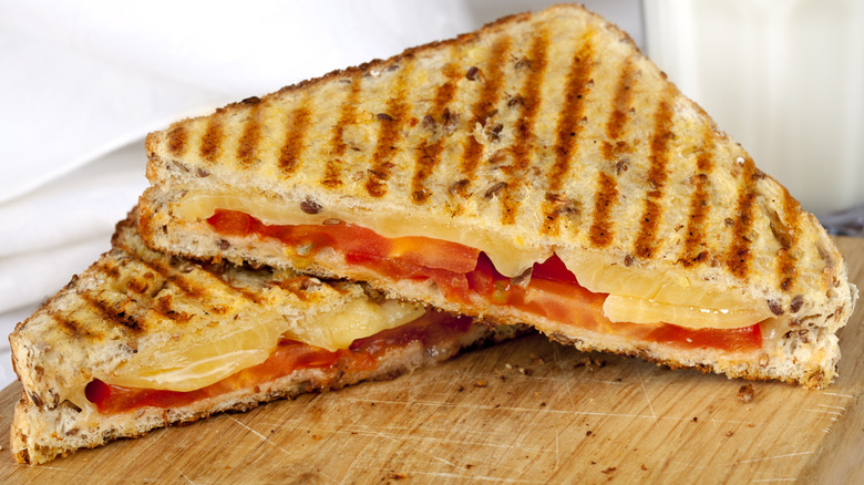 A grilled tomato and cheese sandwich on a wooden board