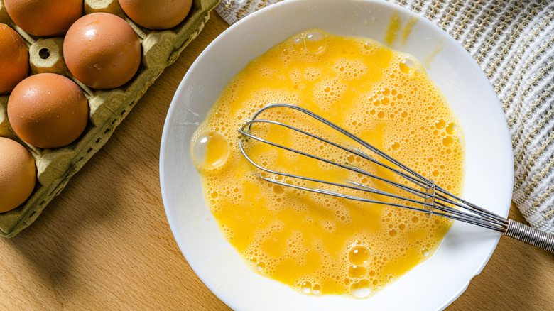Whisked eggs in white bowl