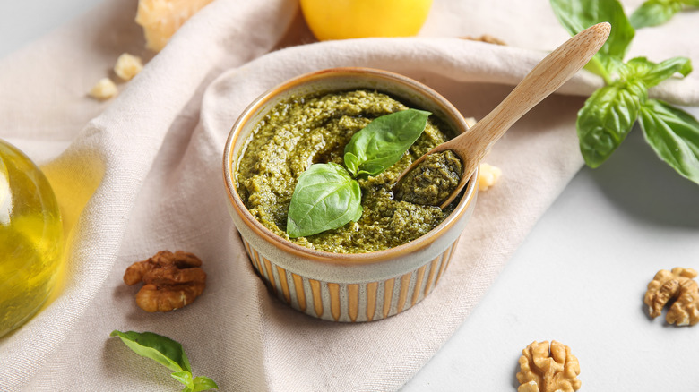 A bowl of pesto with fresh basil and walnuts
