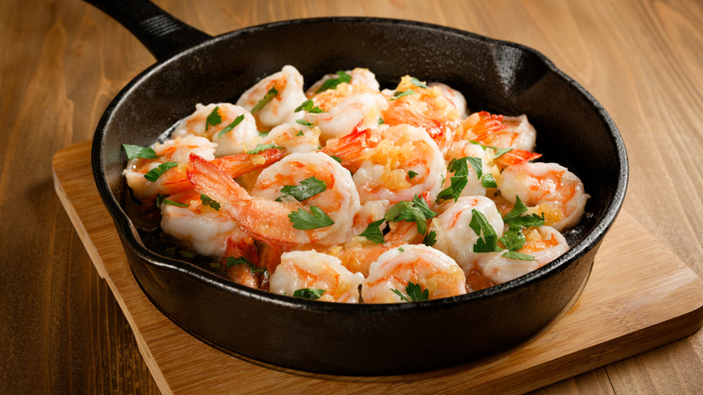 Buttered cooked shrimp in a cast iron skillet, topped with parsley
