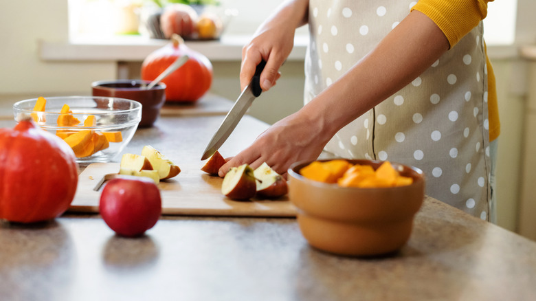 Person slicing some apples and pumpkin.