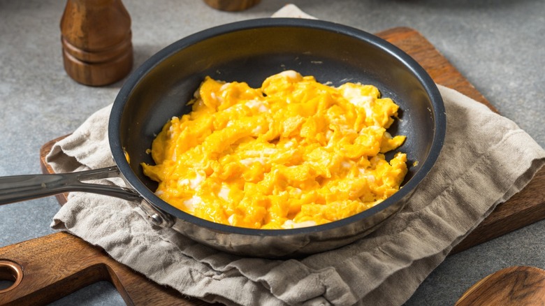Scrambled eggs in a nonstick frying pan on top of a dishtowel