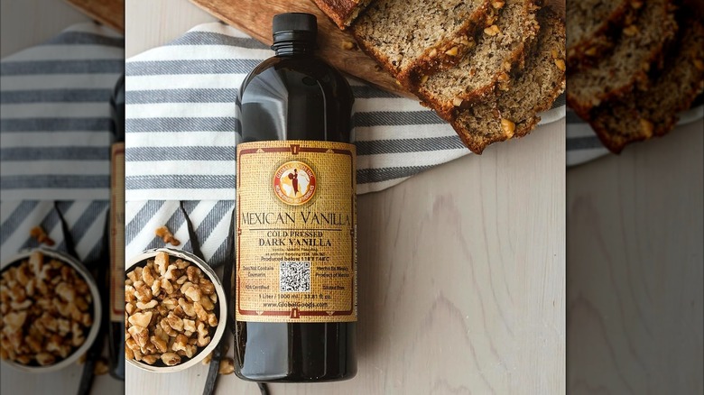 A bottle of pure Mexican vanilla from Global Goods Inc. with sliced sweet loaf and walnuts