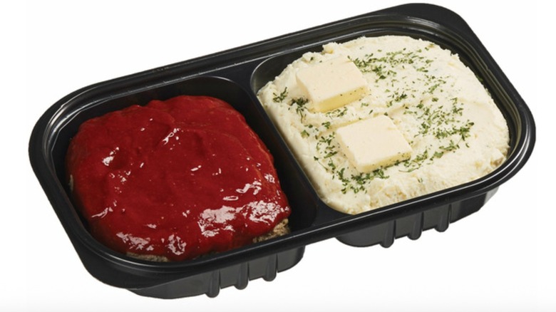 Plastic container of meat loaf and mashed potatoes from Costco that comes with a sauce and two pats of butter on top