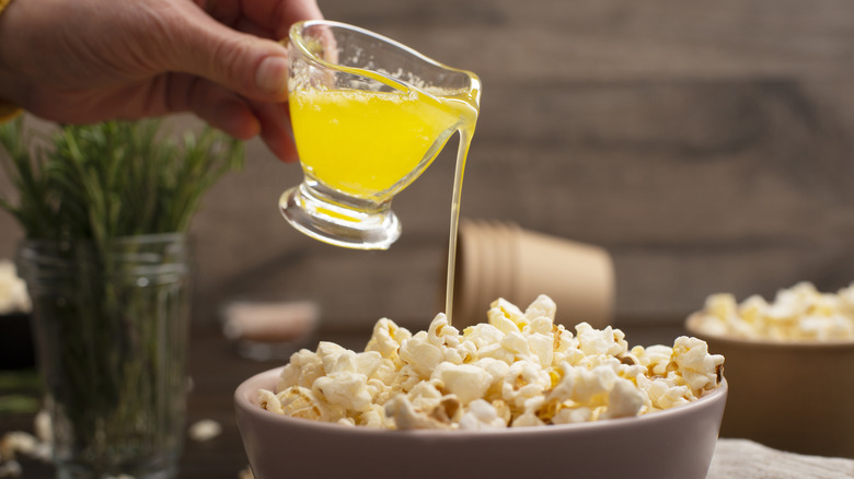Melted butter being poured on a bowl of popcorn