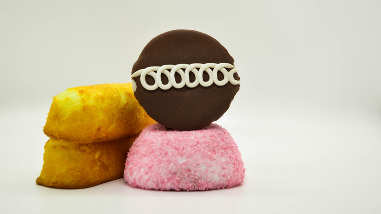 Three types of snack cakes, including Twinkies and Little Debbies sitting on top of each other on a grey surface.