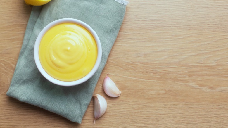 Bright yellow aioli with a kitchen towel on a table