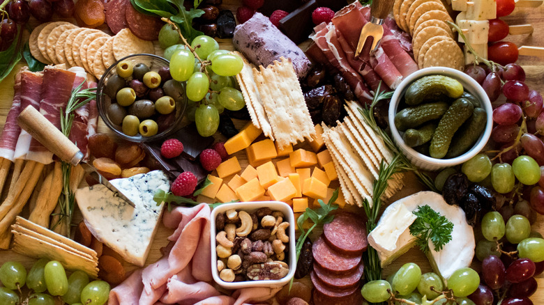 Large charcuterie board with cheeses, meats, crackers, fruits, and nuts