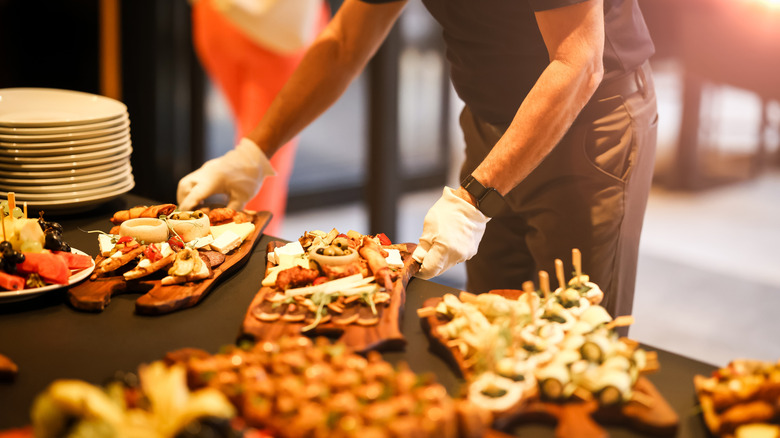 A caterer placing charcuterie boards on a table for an event.