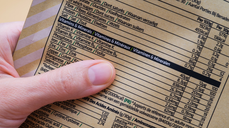 A hand holding a package with nutritional information.
