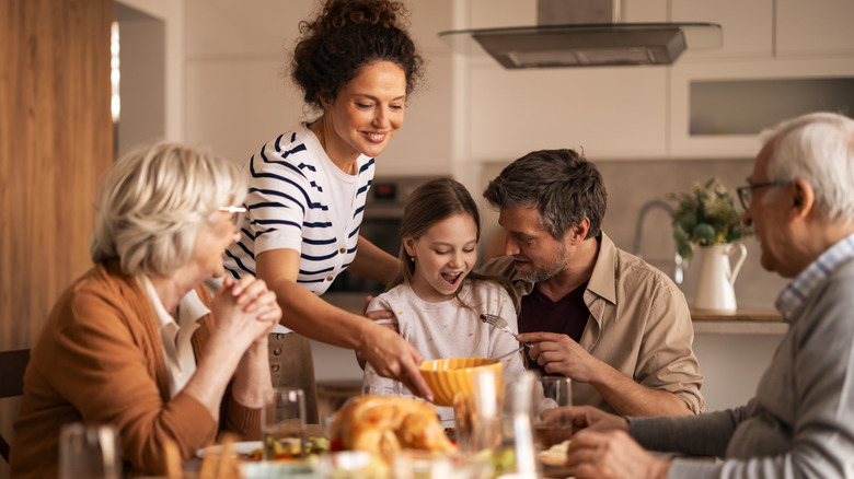 A family sitting down for dinner together with food on the table.
