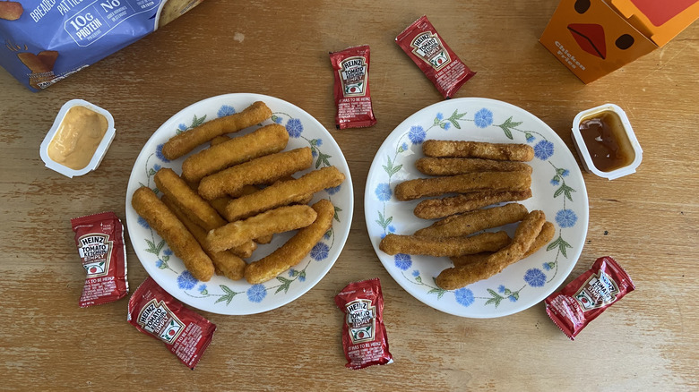 top-down view of both kinds of Chicken Fries on plates surrounded by sauces and containers