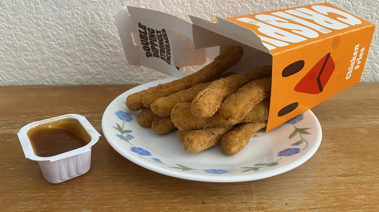 Burger King Chicken Fries container spilling out onto plate beside open dipping sauce