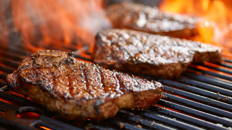 Steaks cooking on a grill over an open flame