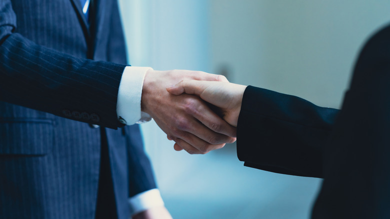 Two people in suits shaking hands.