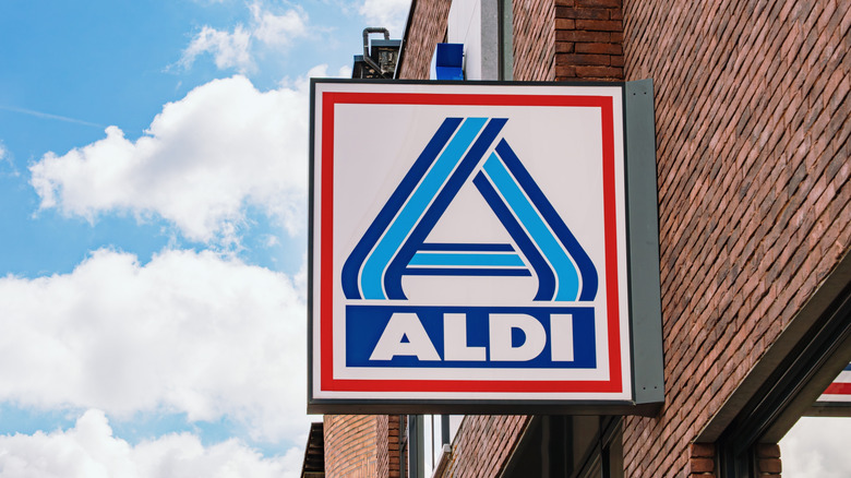 An image of an Aldi Nord sign on a brick wall with a blue sky behind it.