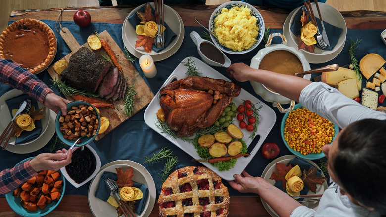 An array of different Thanksgiving dishes served on a long wooden table