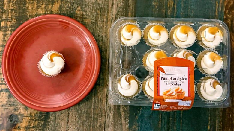 Bake shop Pumpkin spice cupcakes from Aldi in clamshell package next to plate with one mini cupcake