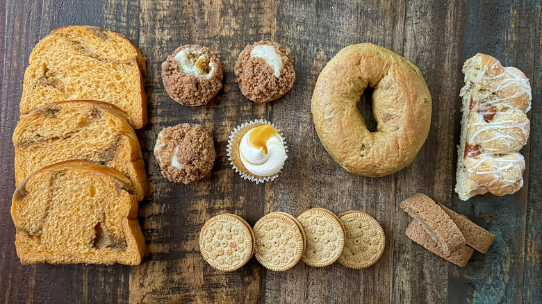 Several Aldi pumpkin spice items on a table, including bagel, sandwich creme cookies, and cupcakes