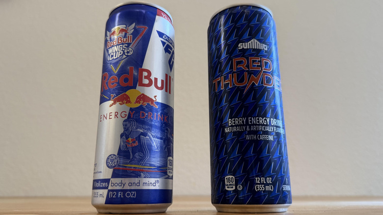low angle shot of Red Bull can beside Red Thunder can