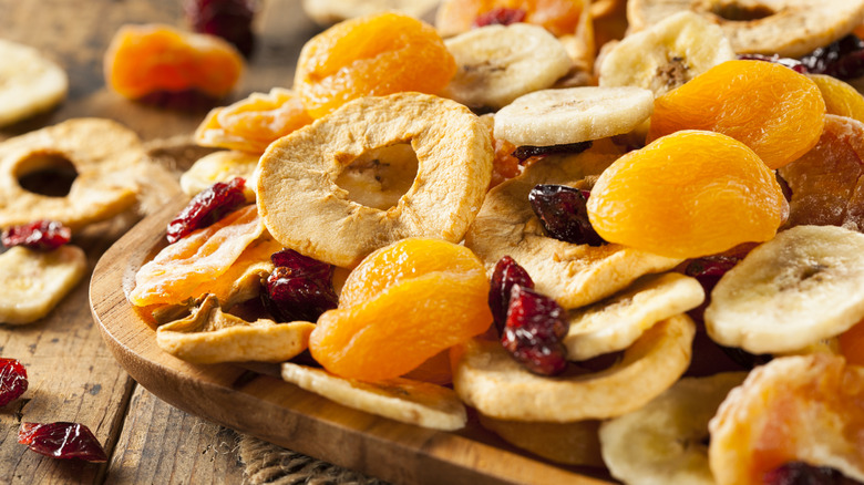 Assortment of dried apples, apricots, and cranberries on wooden board