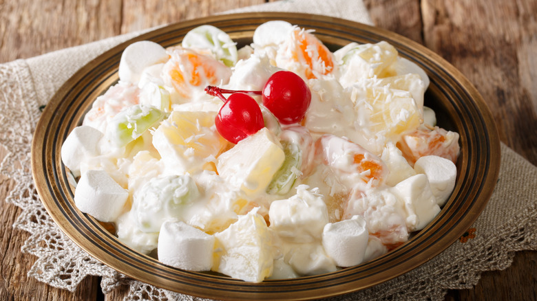 Bowl of ambrosia salad topped with Maraschino cherries.