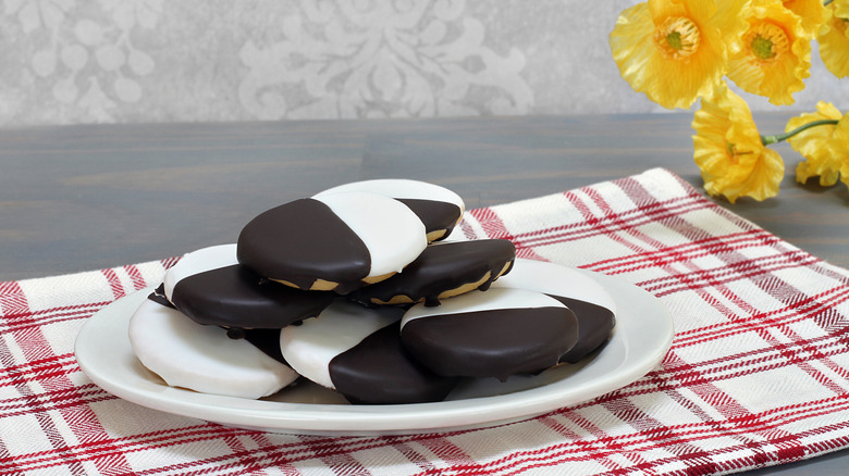 Black and white cookies on a white plate on a red and white towel