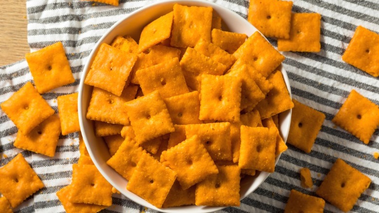 A bowl of Cheez-Its with more scattered around the bowl.