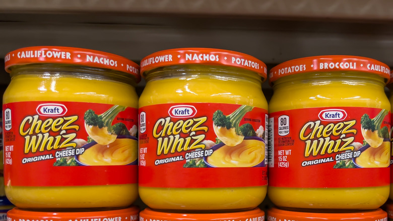 Jars of Cheez Whiz dip on grocery store shelf.