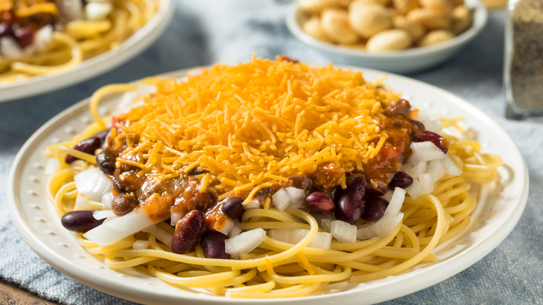 Plate of Cincinnati chili with cheese, beans, onions, and noodles.