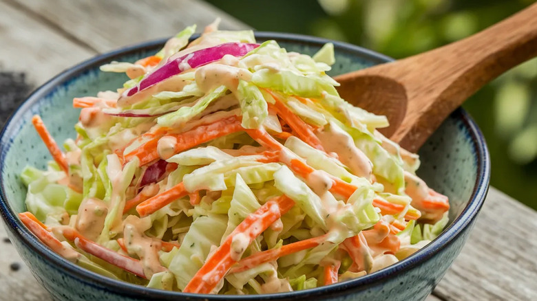 Mayo coleslaw in a blue bowl with a wooden spoon