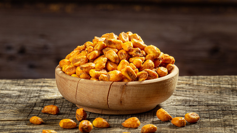 Wooden bowl of roasted, seasoned corn snacks.