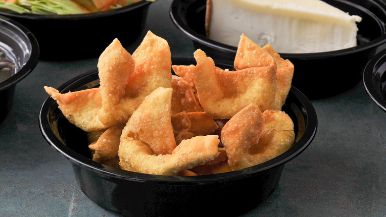 Black plastic bowl of fried Crab Rangoon.