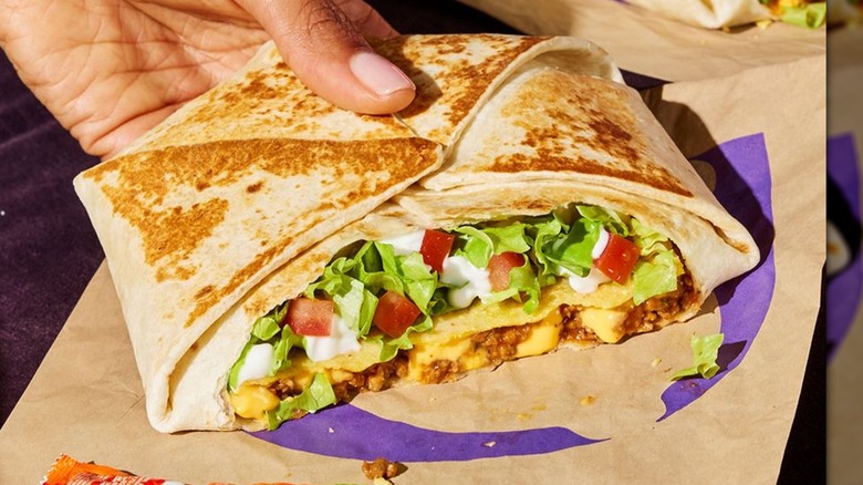 Hand holding Crunchwrap Supreme from Taco Bell.
