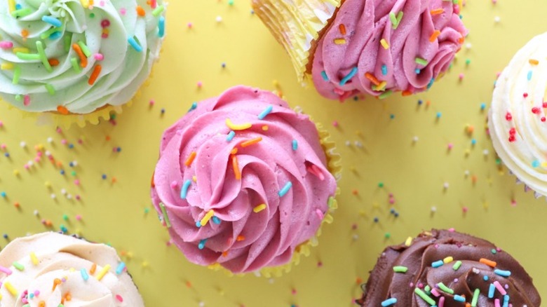 Top-down view of frosted cupcakes with different colored frosting and sprinkles.