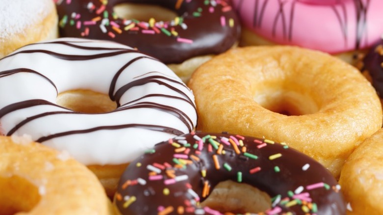 Various glazed and frosted donuts with different patterns lined up on a surface.