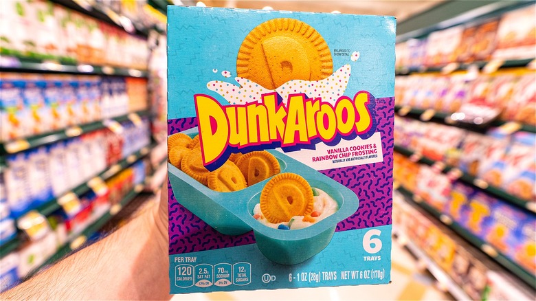 Hand holding a box of Dunkaroos in the snack aisle of a supermarket