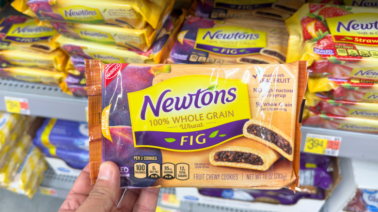 Hand holding package of Fig Newtons inside grocery store.