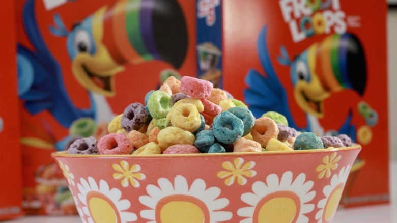 A bowl of Froot Loops with boxes behind it.