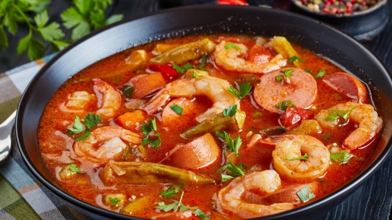 cajun gumbo cooking in a pot with shrimp, vegetables, and various other ingredients