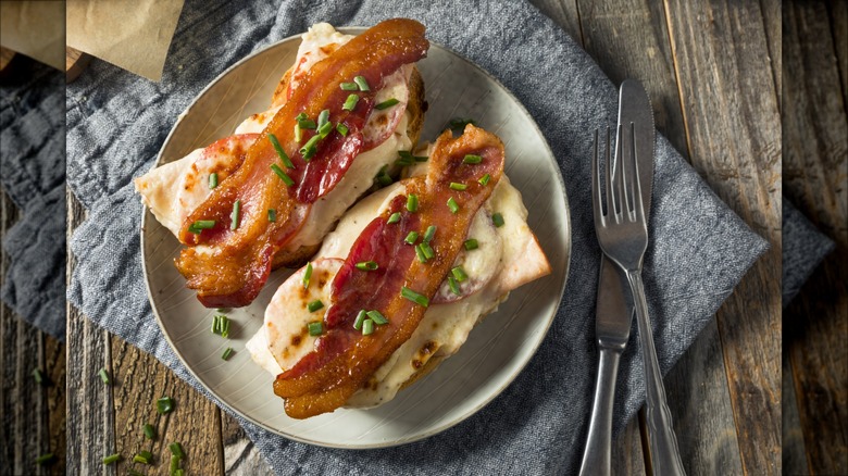 A "Hot Brown" open-faced sandwich with bacon and turkey on plate.