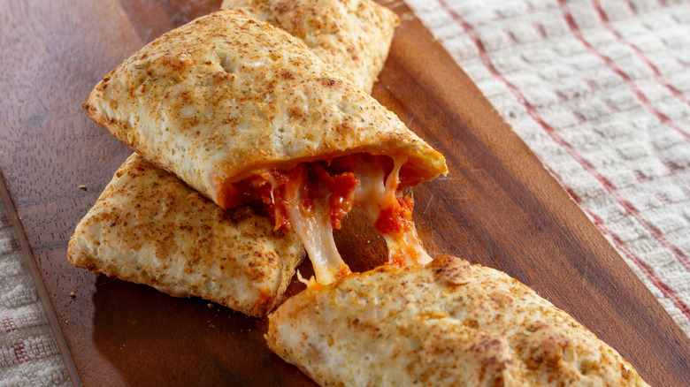Two Pepperoni Pizza Hot Pockets on wooden cutting board.