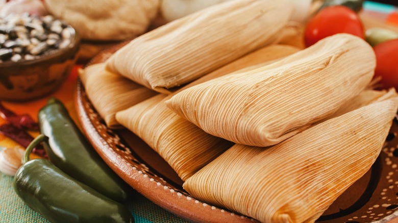 tamales wrapped in corn husks with chilis