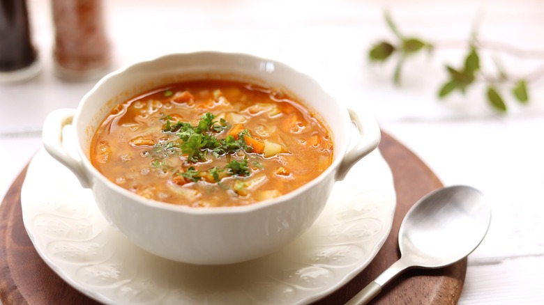 pepper pot soup in white bowl with saucer