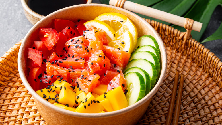 A poke bowl is filled with fresh fish, fruit, and vegetables