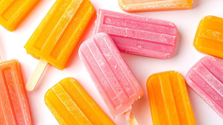 Orange and pink popsicles on a pale pink background