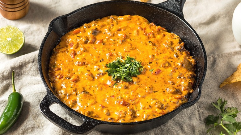 Queso dip in a cast-iron pan topped with fresh cilantro