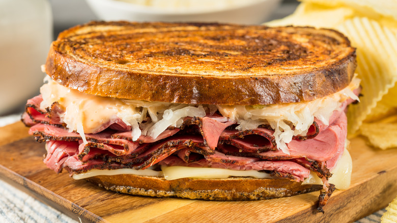 A reuben sandwich sits on a cutting board