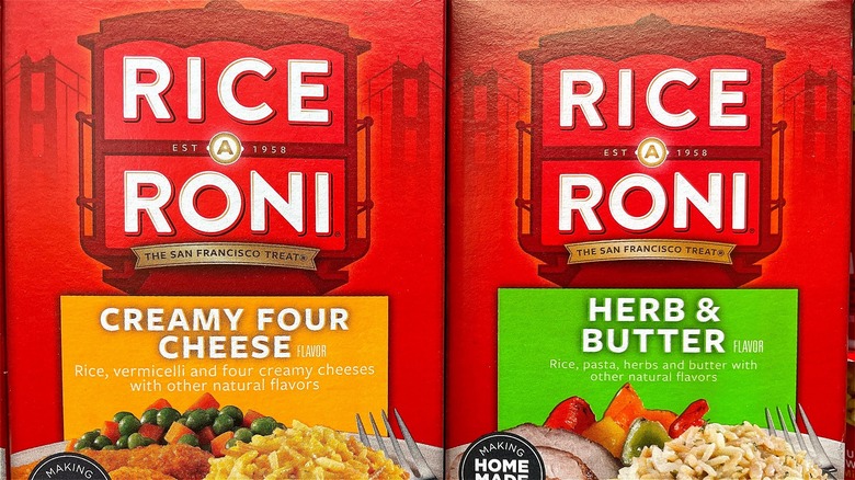 One box of creamy four cheese Rice-A-Roni next to one box of Herb & Butter Rice-A-Roni