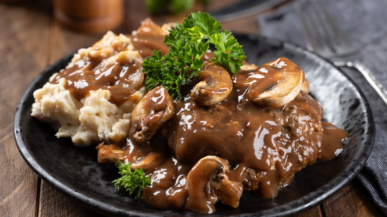 Plate of Salisbury steak, mushrooms, gravy, and mashed potatoes.